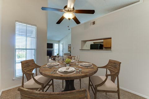 A dining room with a round wooden table set for six.